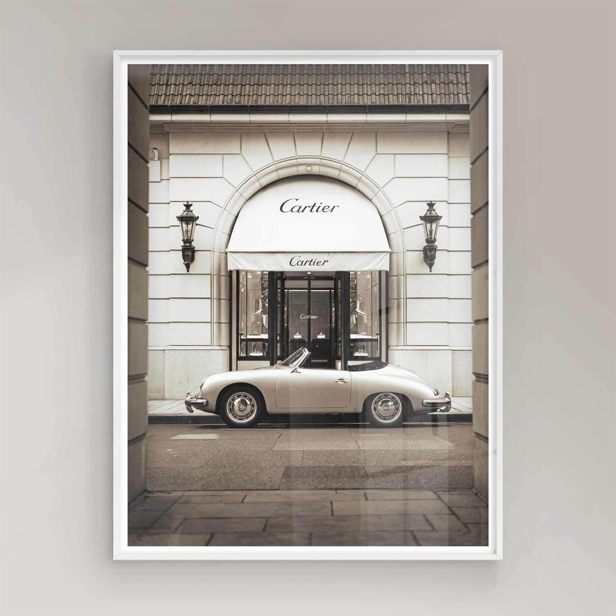 Vintage car parked in front of a Cartier store entrance on a white frame