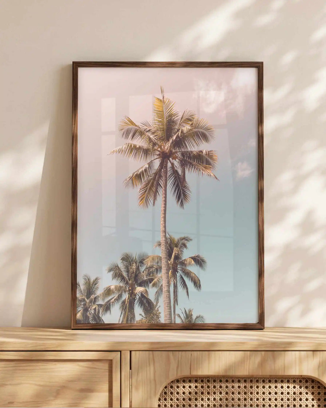 Tall tropical palm tree framed print photographed against a soft pink and blue pastel sky, creating a dreamy coastal wall art print inspired by endless summer living.