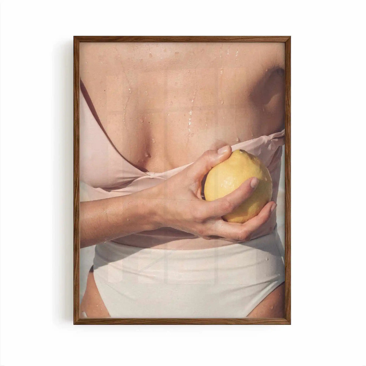 Editorial Mediterranean photography framed print showing a fresh lemon held against sun-kissed skin with soft neutral tones and warm citrus colours.
