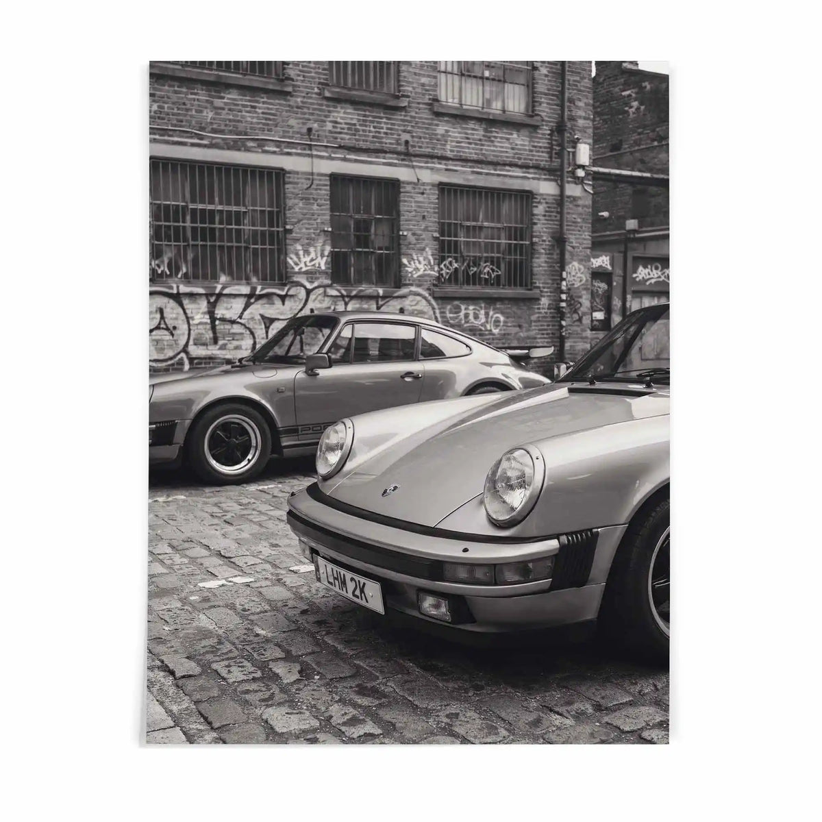 Nine Eleven Porsche 911 black and white wall art by After Hours Gallery featuring two classic sports cars in an industrial urban setting.